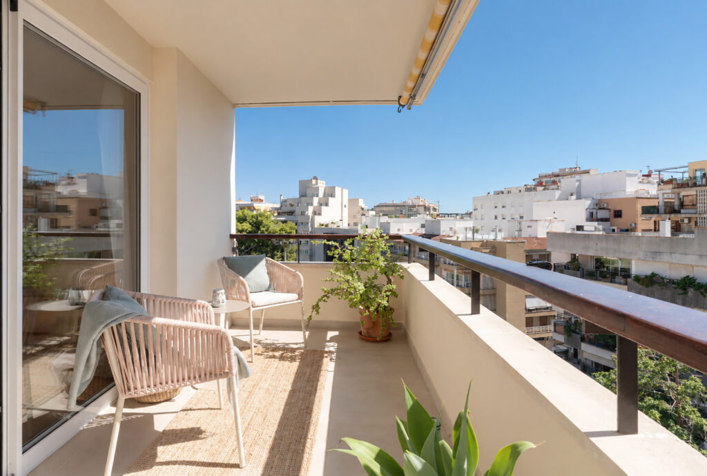 Balcón exterior con dos butacas, vegetación y vistas al entorno urbano