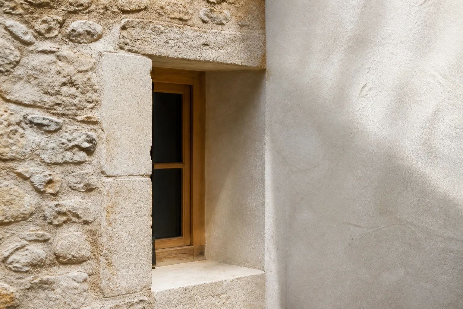 Detalle de piedra caliza, revoco de cal y carpintería de madera en una rehabilitación mediterránea