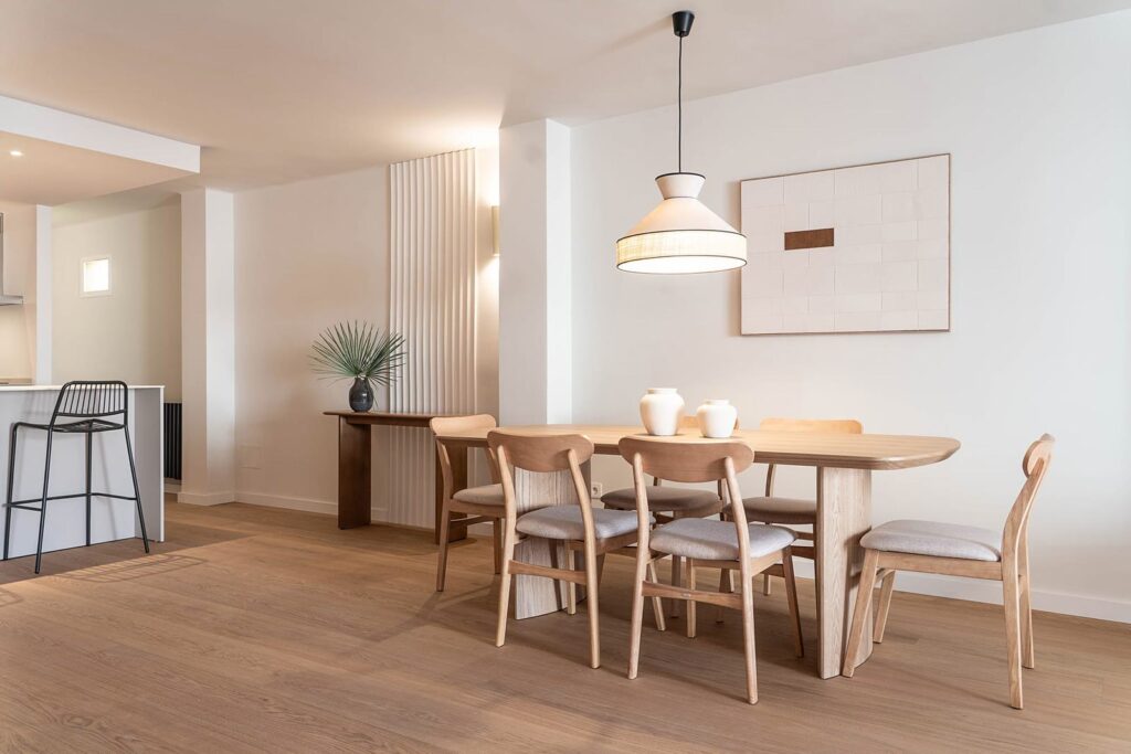 Comedor con mesa de madera y lámpara suspendida junto a la cocina