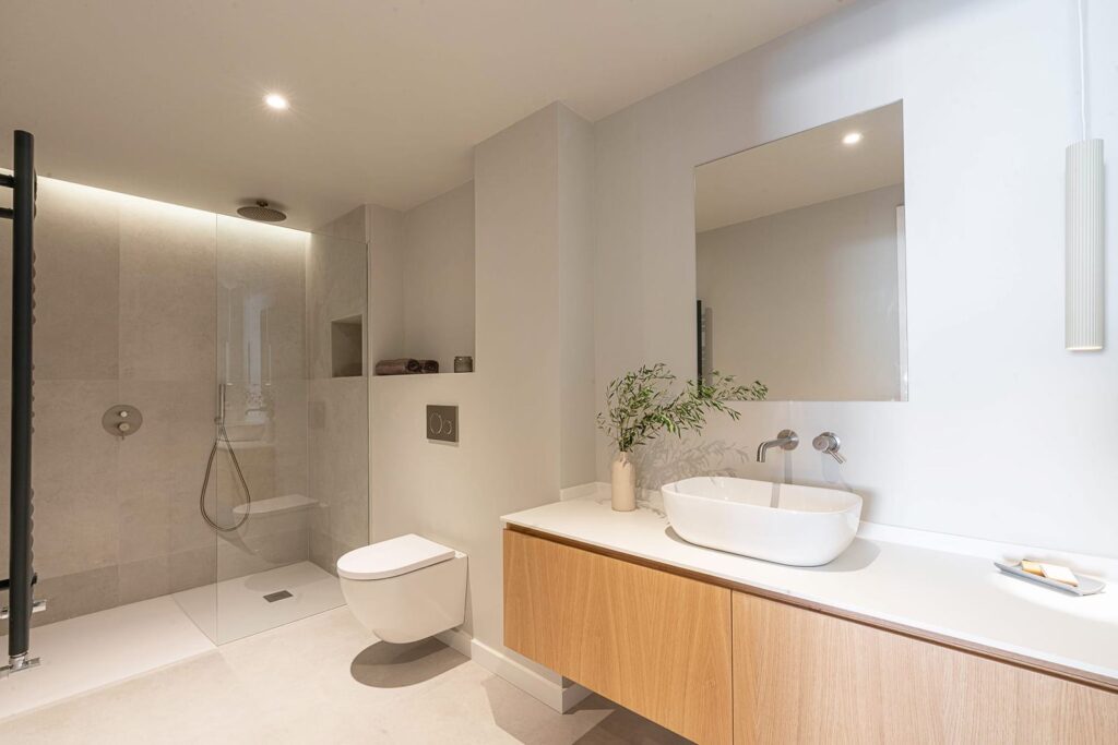 Baño con ducha acristalada y mueble de lavabo de acabado madera