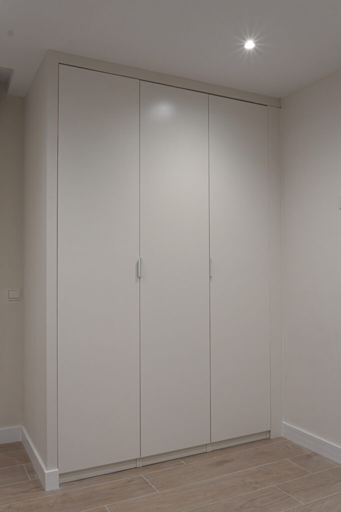 Armario empotrado de puertas blancas junto al pavimento porcelánico imitación madera