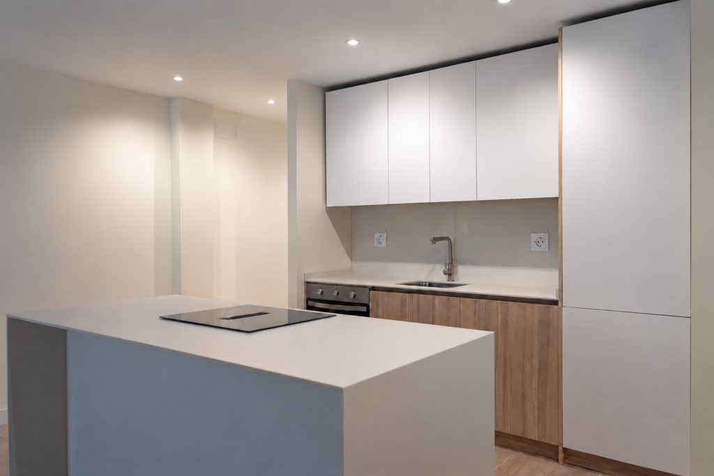 Vista lateral de la cocina con placa de cocción, horno y frentes blancos y acabado madera