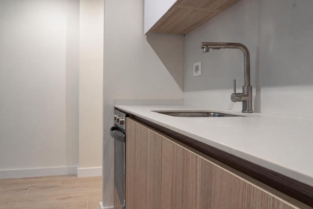 Detalle del fregadero y la encimera clara con muebles de acabado madera