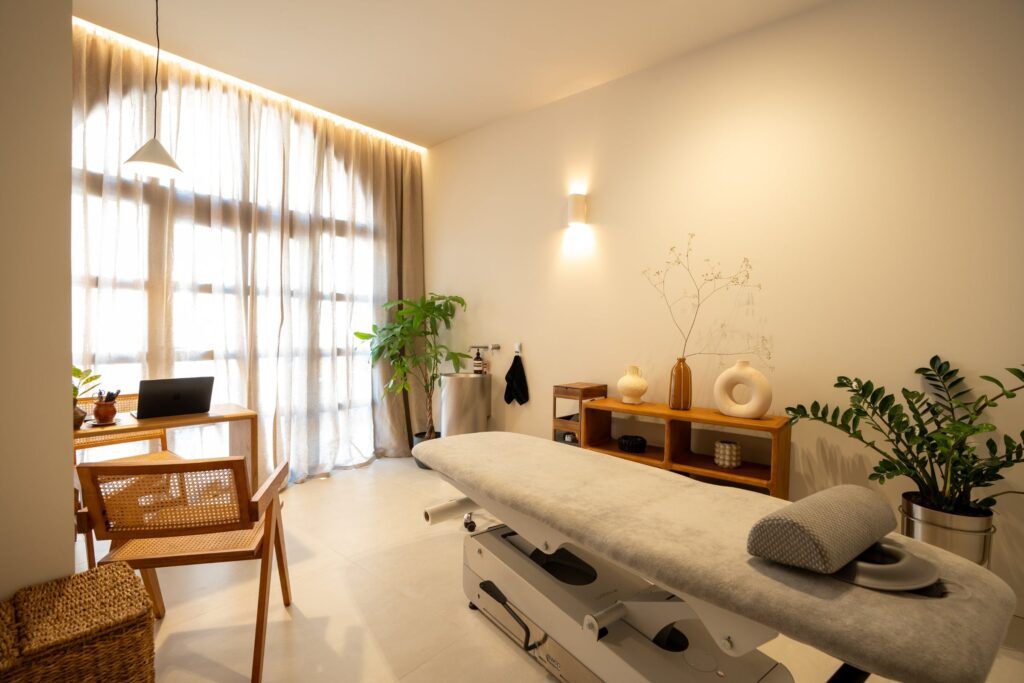 Sala de tratamiento con camilla, cortinas de lino y luz cálida