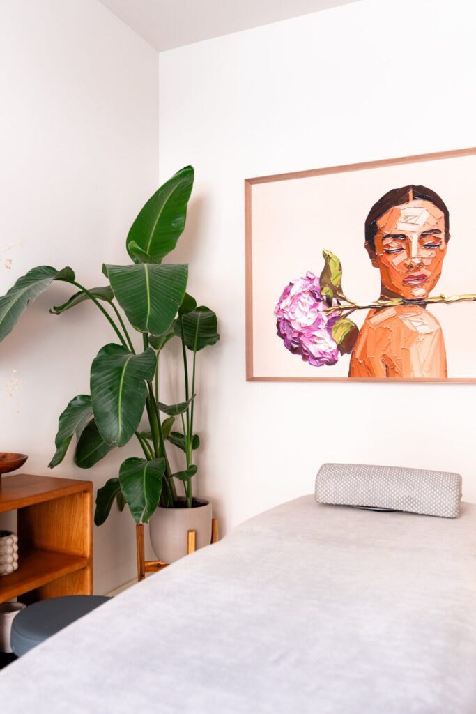 Sala de masaje con planta, mueble de madera y cuadro