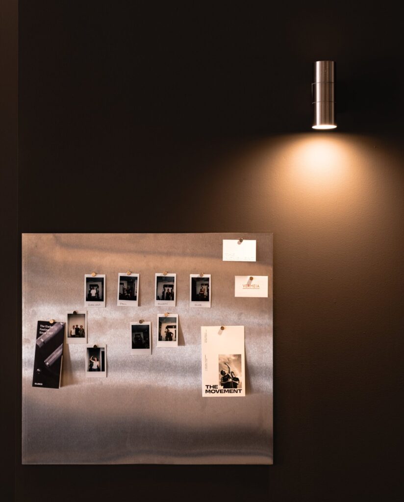 Panel de acero con fotos y aplique de luz sobre pared oscura